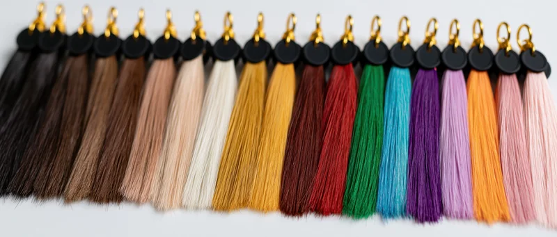Row of hair extension color swatches arranged in gradient on white surface