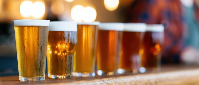 Row of craft beer glasses lined up on wooden bar counter
