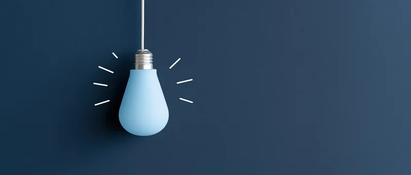 Blue lightbulb hanging from white cord against dark blue background with radiating lines suggesting illumination