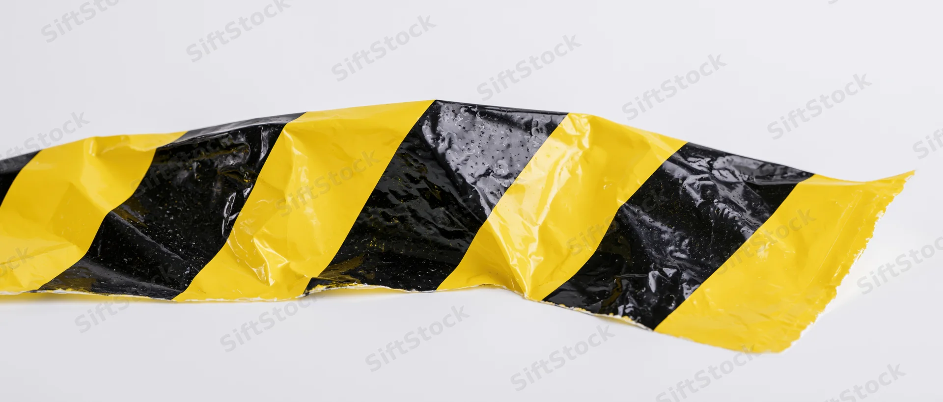 Crumpled black and yellow diagonal hazard tape on white background