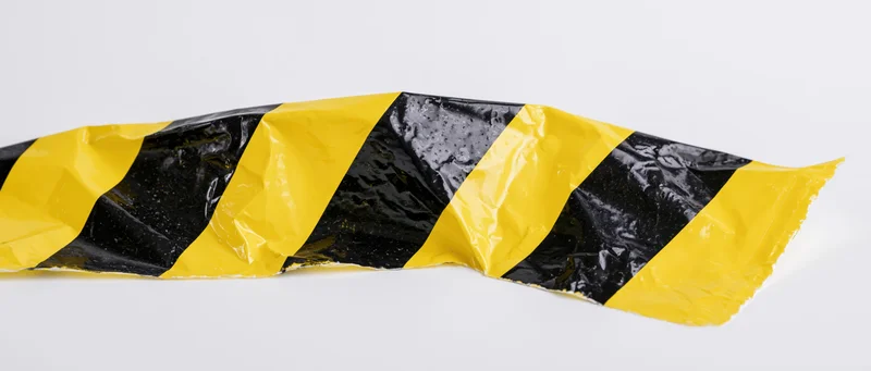 Crumpled black and yellow diagonal hazard tape on white background