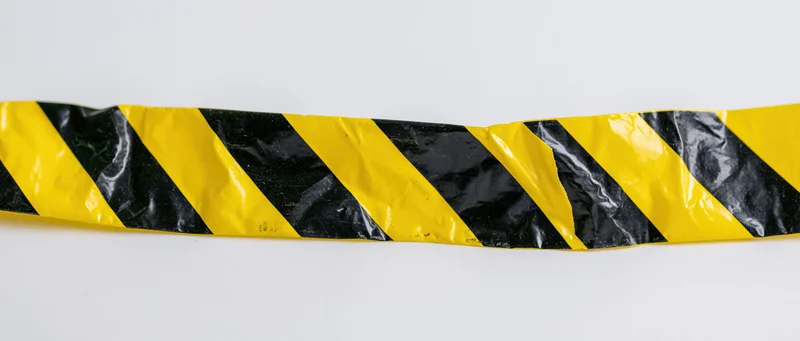 A single strip of yellow and black diagonal-striped hazard tape on a white background