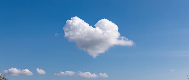 Heart-shaped cloud floating in a clear blue sky