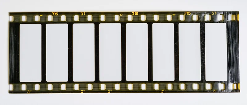 Blank 35mm film strip with perforated edges laid flat on white background