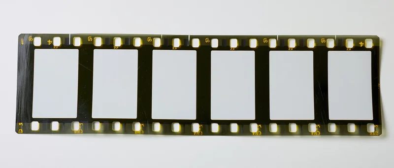 Blank 35mm film strip with perforated edges laid flat on white background