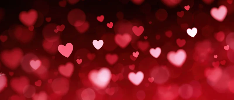 Abstract red bokeh background with glowing heart shapes for valentines day