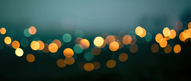 Blurred circular lights in warm tones against a dark teal background