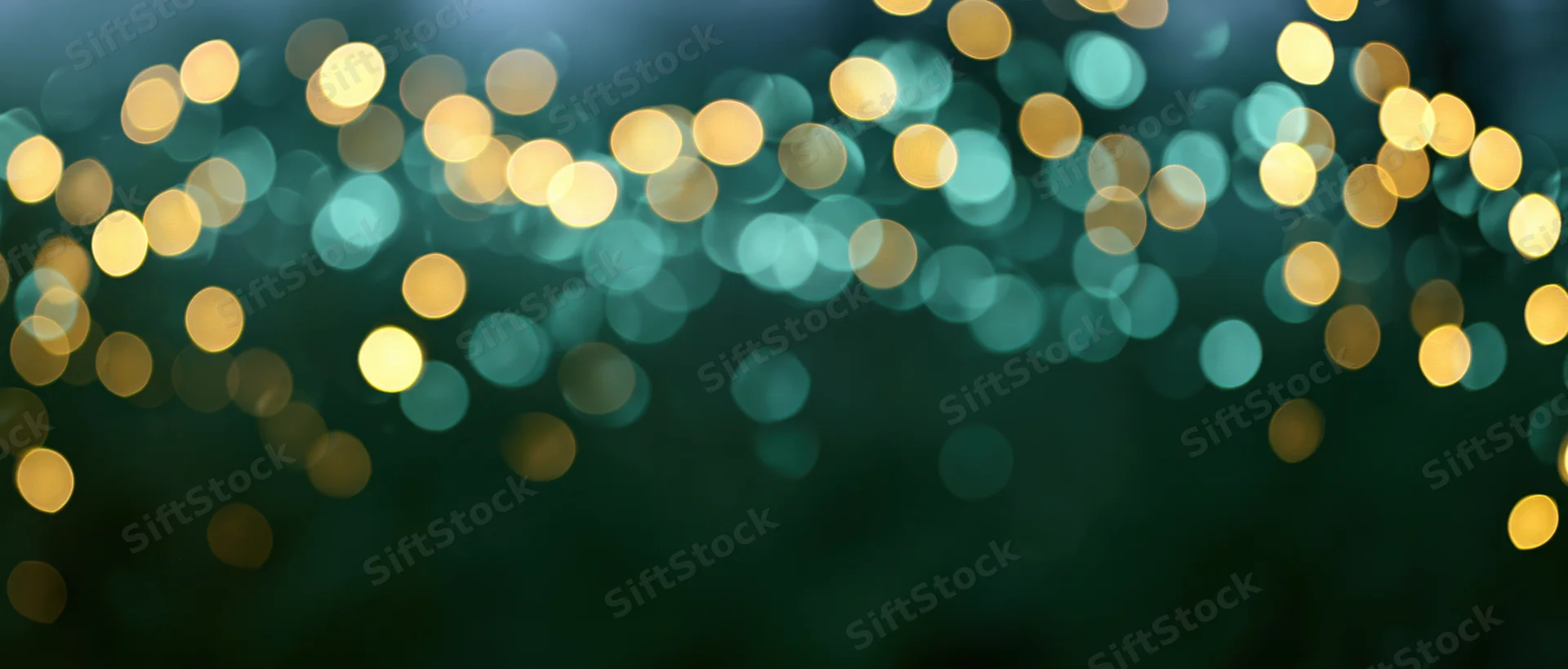 Abstract bokeh background with blurred golden and teal lights scattered across dark space