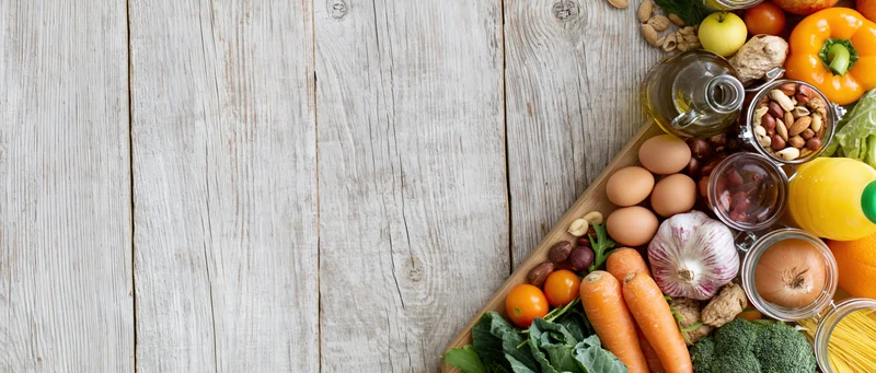 Fresh groceries and pantry staples arranged on a wooden tabletop with copyspace