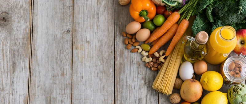 Fresh groceries and pantry staples arranged along the right side of a rustic wooden table