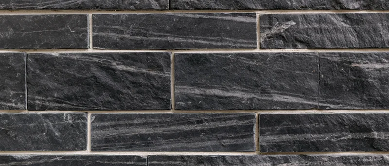 Black marble tiles arranged in a brick pattern on a wall surface