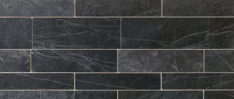 Black marble tiles arranged in a grid pattern on a wall surface