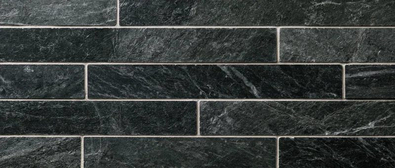 Black marble tiles arranged in a rectangular grid on a wall