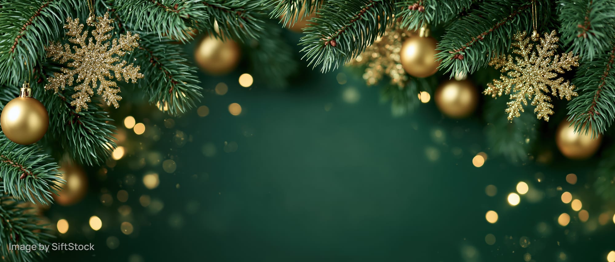 Christmas pine branches with golden ornaments and snowflakes framing a dark green background with bokeh lights and copyspace