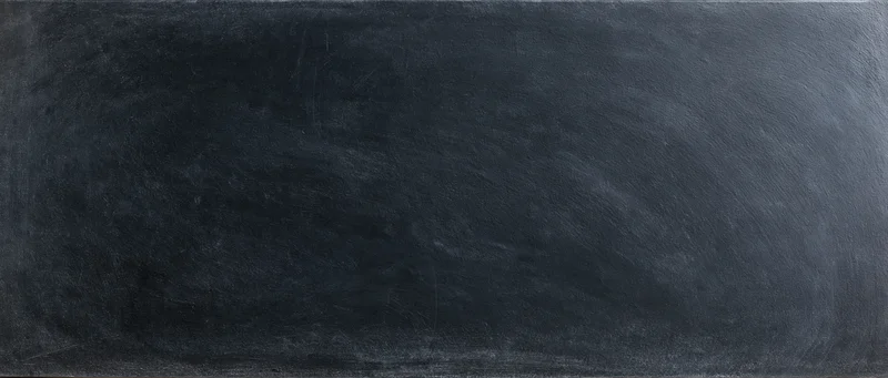 Close-up of a dark charcoal blackboard surface with smudged chalk residue and visible texture
