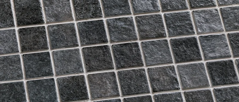 Close-up of black and gray glass mosaic tiles arranged in a grid pattern on a wall surface