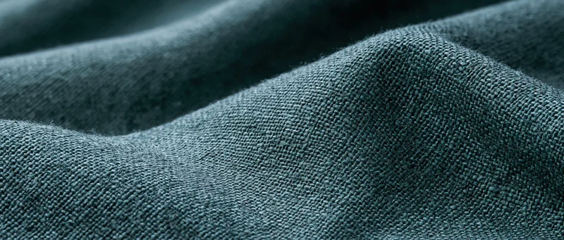 Close-up of dark forest green linen fabric with visible weave and texture filling the frame