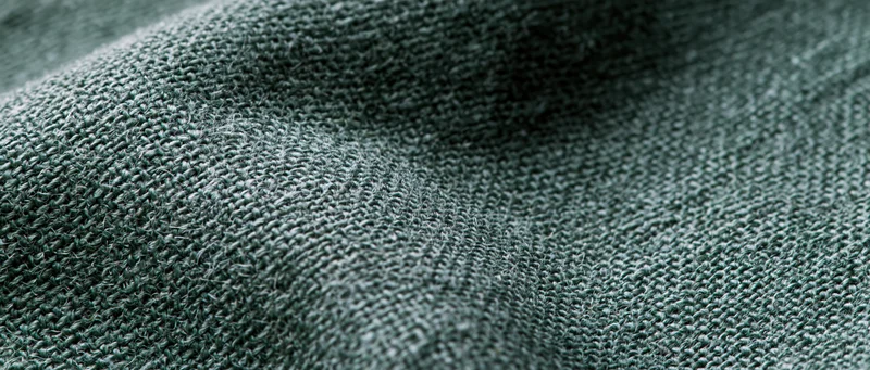 Close-up of dark forest green linen fabric with visible weave and texture in flat lay arrangement