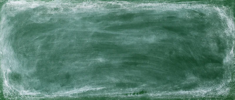 Close-up of a green chalkboard surface with smudged white chalk marks in a classroom setting