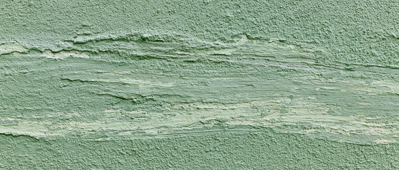 Close-up of rough green painted concrete wall surface with horizontal texture and wear