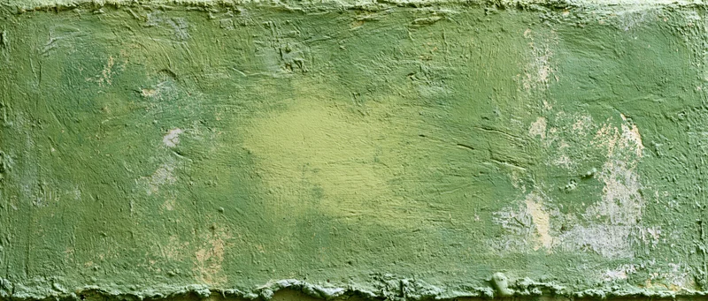 Close-up of a rough green plastered wall with peeling paint and weathered texture