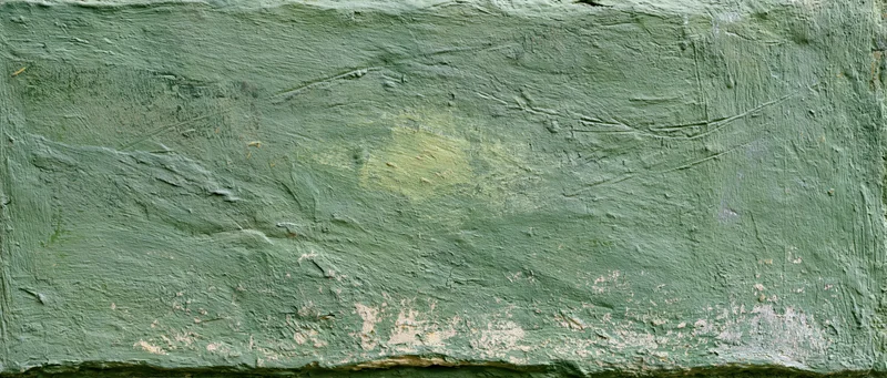 Close-up of a rough green plastered wall with peeling paint and cracks