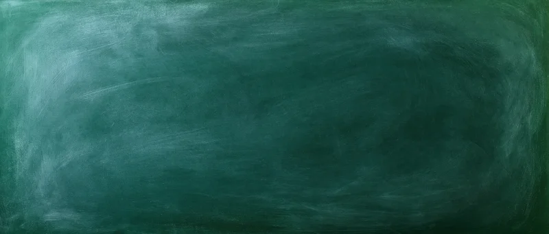 Close-up of a worn green chalkboard surface with smudged residue and erased marks filling the frame