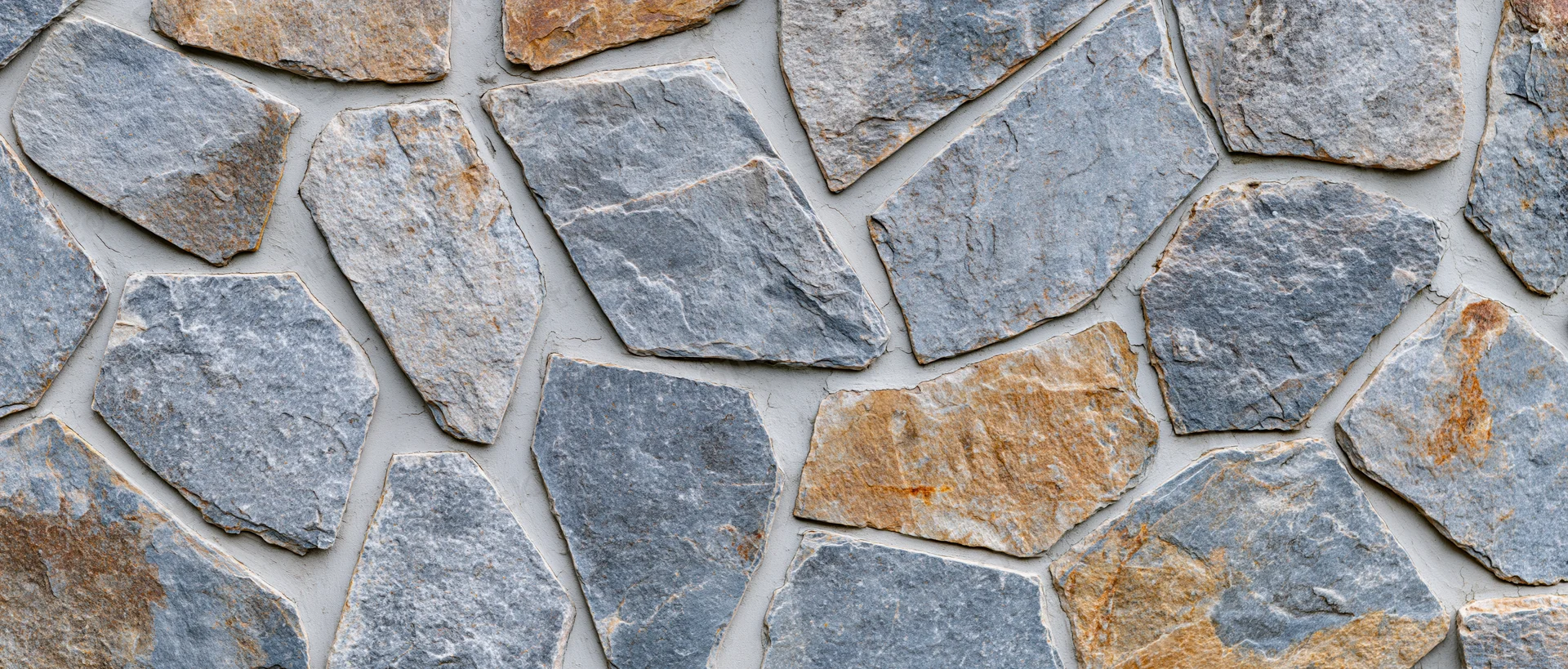 Irregular dry-stack stone wall surface with gray and beige rocks arranged in a natural pattern