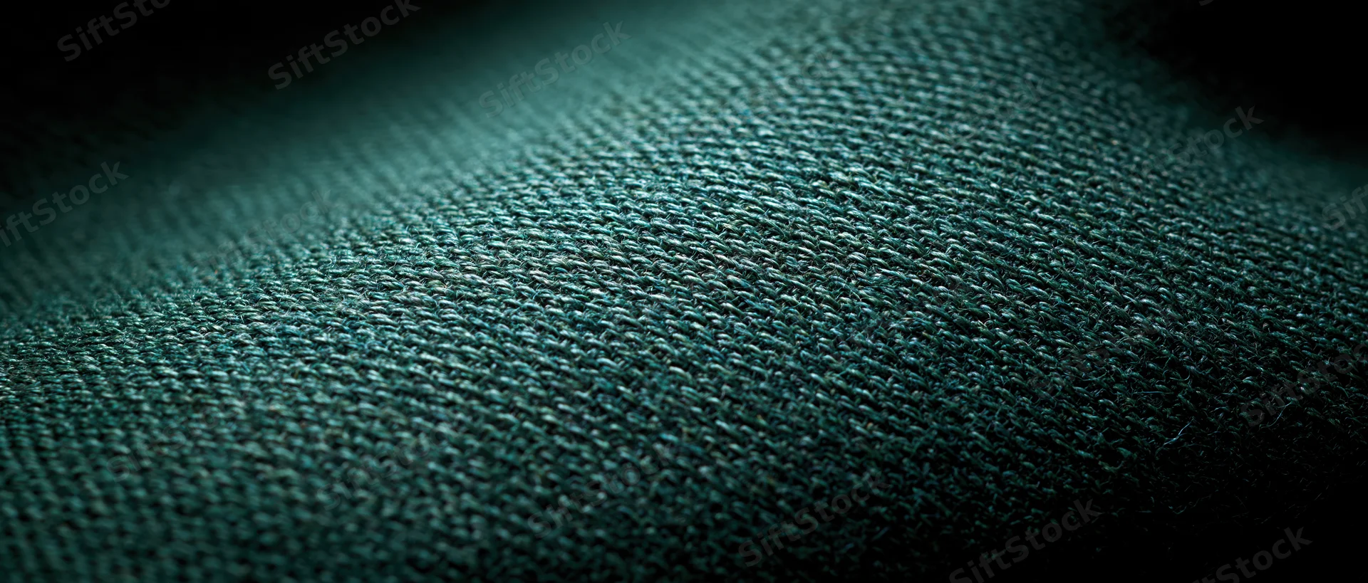 Close-up of dark green woven textile fabric showing detailed weave texture
