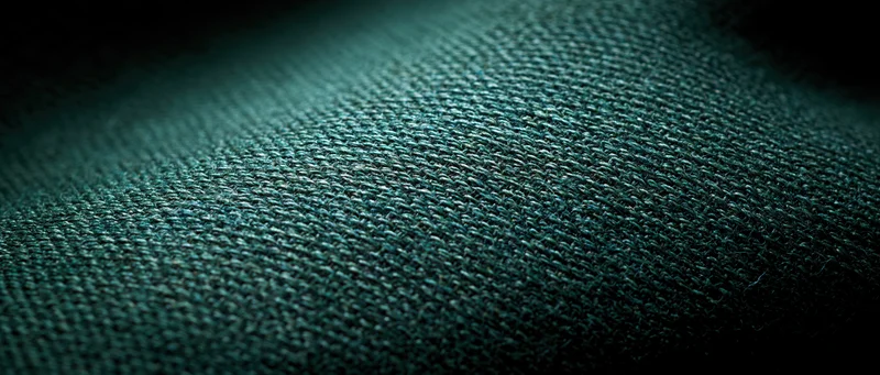 Close-up of dark green woven textile fabric showing detailed weave texture