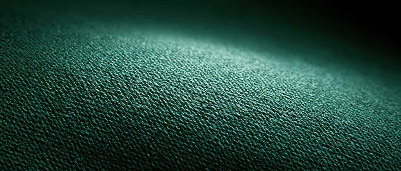 Close-up of dark green woven textile fabric with visible weave pattern and soft lighting gradient