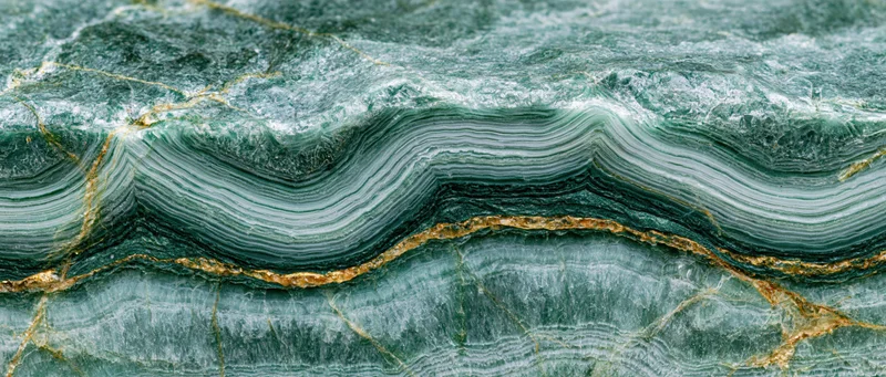Close-up of polished green marble surface with layered veining and gold inclusions