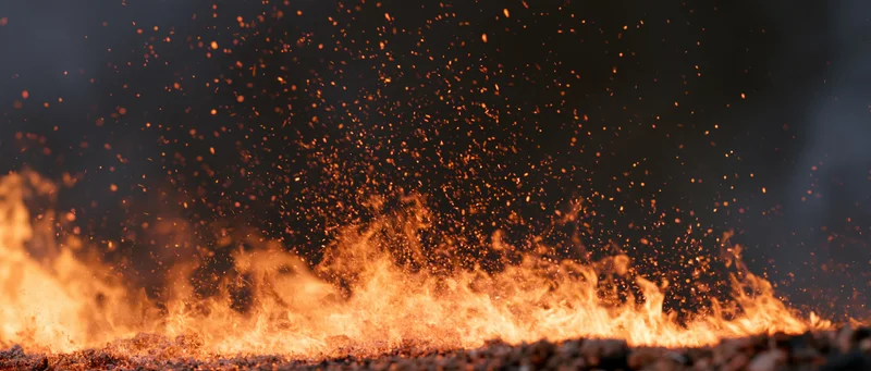 Fire flames erupting upward from ground at bottom of frame against dark background
