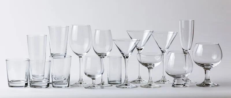Collection of empty glassware arranged in two rows on white surface