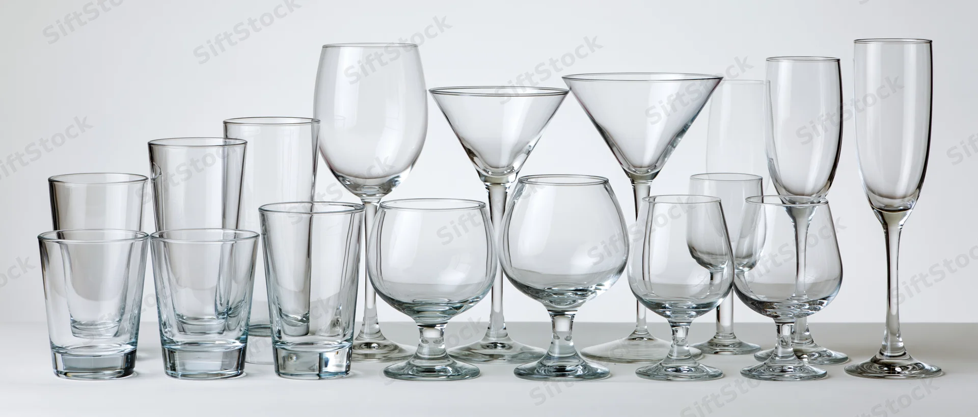 Empty glassware arranged in two rows on a white surface