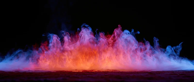 Colored smoke and flame-like tendrils rising from a flat surface against black background