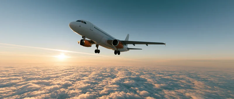 Commercial passenger jet with landing gear extended flying above clouds at sunrise