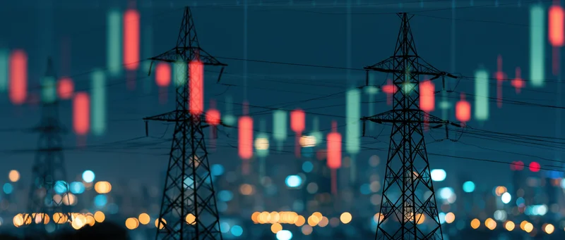 Electricity transmission towers overlaid with stock market candlestick chart against city night lights