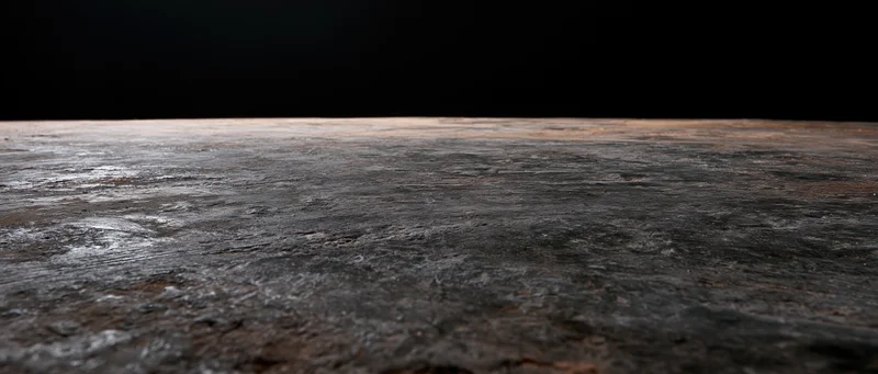 Dark concrete floor receding into black background with visible texture and depth