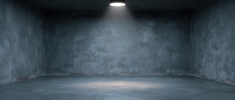 Empty concrete studio room with spotlight on textured cement walls and floor