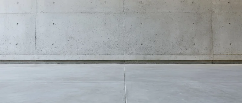 Polished concrete floor meeting a smooth concrete wall in a minimalist interior space