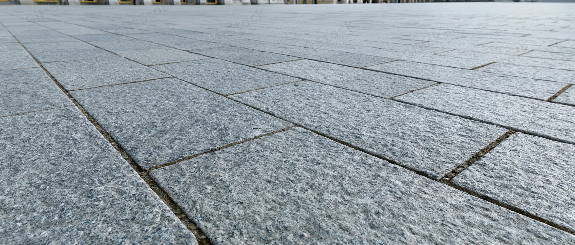Close-up of gray stone tiles forming a paved urban plaza surface