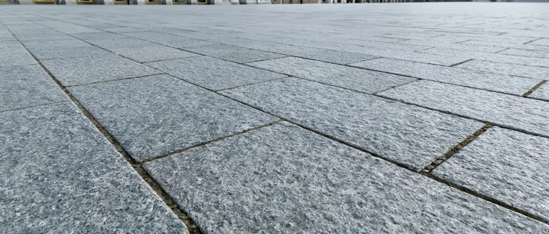 Close-up of gray stone tiles forming a paved urban plaza surface