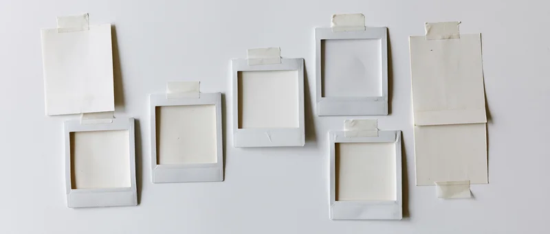 Blank instant photo frames taped to a white surface in a flat lay arrangement