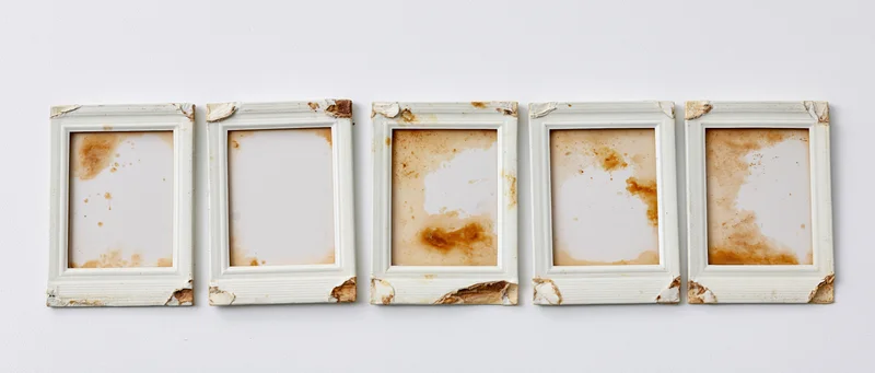 Five empty instant photo frames arranged in a horizontal row on a white wall