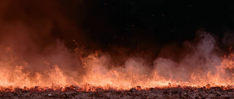 Flames and embers rising from burning ground at night