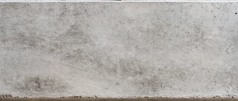 Wide flat concrete wall surface filling the frame with rough texture and gray tone
