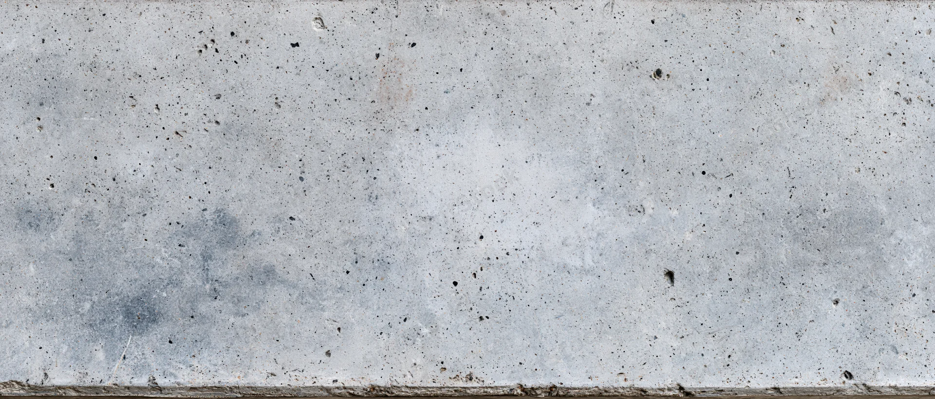 Wide panoramic view of a weathered concrete wall surface with speckles and stains