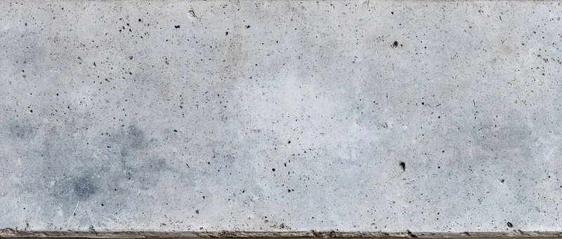 Wide panoramic view of a weathered concrete wall surface with speckles and stains