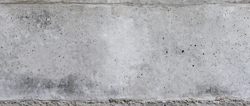 Wide panoramic view of a weathered concrete wall surface with speckled texture and horizontal lines